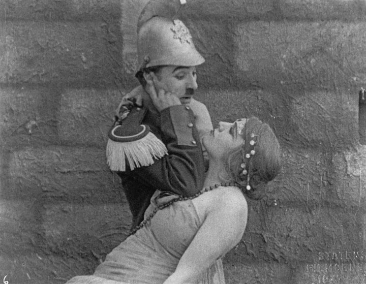 Darn Hosiery (Charlie Chaplin) relaxes on Carmen (Edna Purviance). 